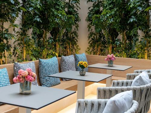 two tables and chairs with vases of flowers on them at DAYS City Suites in Patra