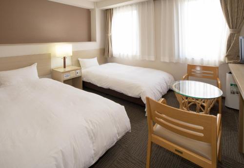 um quarto de hotel com duas camas e uma mesa em Kur and Hotel Shinshu em Shiojiri