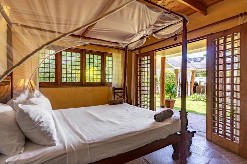 a bedroom with a canopy bed in a room with windows at private pool cottage diani beach in Diani Beach