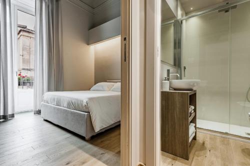 - une chambre avec un lit, un lavabo et un miroir dans l'établissement Ferrini Home - Rindone 6, à Catane