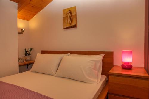 a bedroom with a bed with a pink lamp on a night stand at Skalopati Studios & Villa in Panormos Skopelos