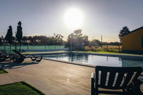 a swimming pool with two chairs and a bench at Quinta do Pica-Pau Amarelo in Grândola
