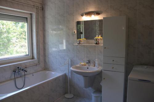 uma casa de banho com um lavatório e uma banheira e um lavatório em Centrum Apartman em Fonyód