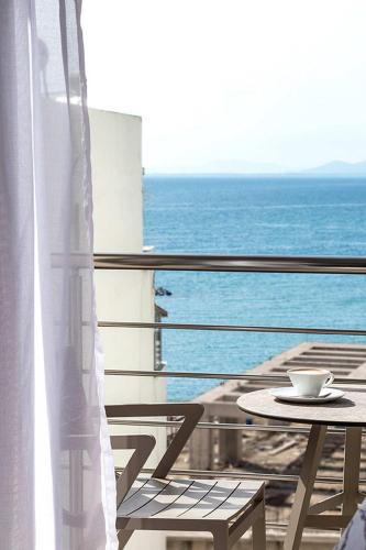 a table and chair on a balcony with the ocean at DAYS City Suites in Patra