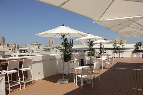 a balcony with tables and chairs and white umbrellas at Cinema Hotel - an Atlas Boutique Hotel in Tel Aviv