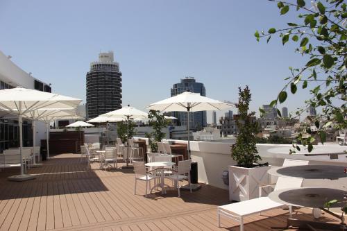 a rooftop patio with tables and chairs and umbrellas at Cinema Hotel - an Atlas Boutique Hotel in Tel Aviv