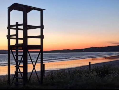 einen Rettungsturm am Strand bei Sonnenuntergang in der Unterkunft Pension Paxaro Negro in Sanxenxo