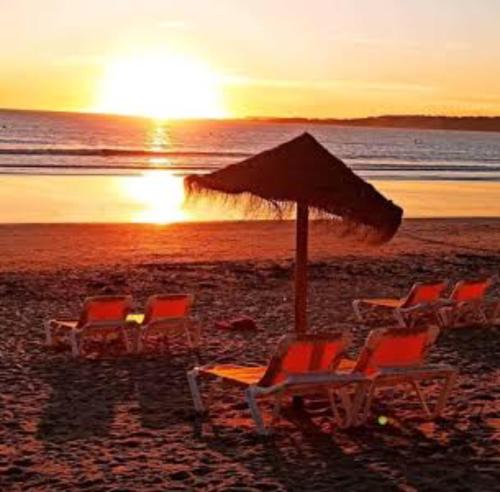 a group of chairs and an umbrella on a beach at Pension Paxaro Negro in Sanxenxo