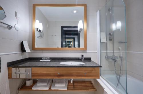 a bathroom with a sink and a mirror and a shower at Original Sokos Hotel Kimmel Joensuu in Joensuu
