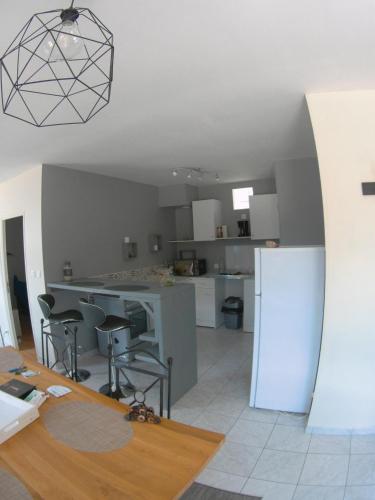 a kitchen with a table and chairs and a refrigerator at Au bonheur des Anes - Gîte Idylle in Le Quesnoy-en-Santerre