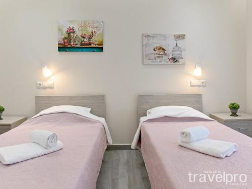 two beds in a room with pink sheets and towels at Sabbia Apartments Seafront by TravelPro Services- Nea Moudania Halkidiki in Nea Moudania