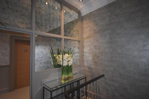 a staircase with a vase of flowers on a glass table at Lincombe Hall Hotel & Spa - Just for Adults in Torquay