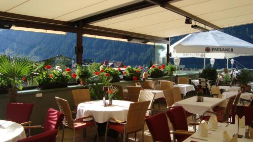 a restaurant with white tables and chairs and flowers at Hotel Ländenhof Superior in Mayrhofen