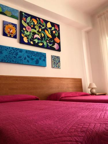 a bedroom with two beds with red sheets and paintings at Al Saliceto Hotel in Patti