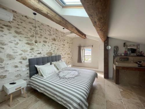 a bedroom with a bed and a stone wall at Appartement de charme Sud Luberon classé 4 étoiles in Puyvert