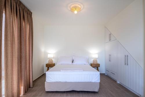 a bedroom with a white bed and two lamps at Remezzo Aqua Blue Maisonette in Livadi Astypalaias
