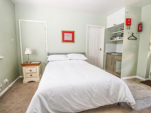 a bedroom with a large white bed and a kitchen at Karibu in Worthing