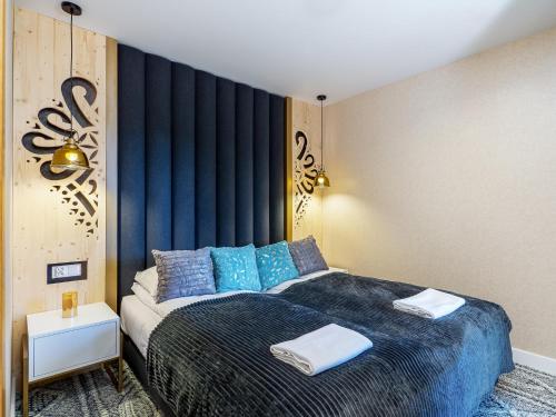 a bedroom with a large bed with blue pillows at Aparthotel Góralski Spa 2 in Białka Tatrzanska