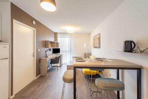 une cuisine avec une table et des tabourets dans une pièce dans l'établissement Auriol, à Toulouse