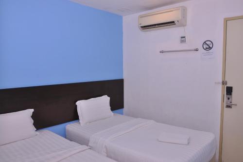 two beds in a room with a blue light at Kuching Transit Inn in Kuching
