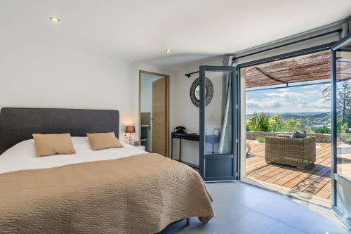 een slaapkamer met een bed en een glazen schuifdeur bij Villa Domitia Chambre d'Hôtes Luberon in Bonnieux