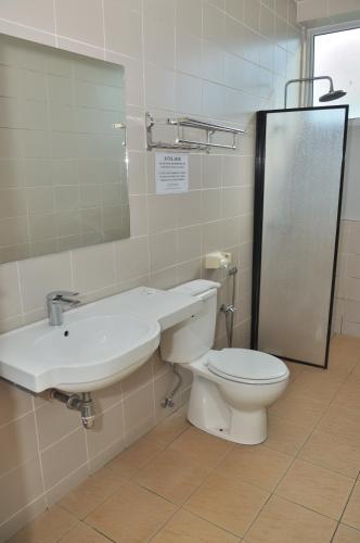 a bathroom with a toilet and a sink and a mirror at Kuching Transit Inn in Kuching