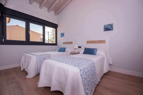 2 łóżka w białym pokoju z oknem w obiekcie AdosadoDuplex Marea Baja 1 Zona Playa Ideal familias parejas y amigos w mieście Llanes