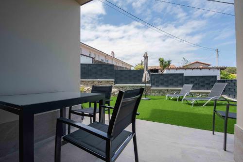 a patio with chairs and a table and a lawn at Adosado Marea Baja 1 zona de playa y montaña in Llanes