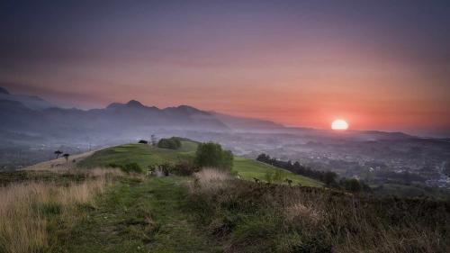 a sunrise on a hill with the sun setting at Adosado Marea Baja 1 zona de playa y montaña in Llanes