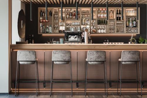 a bar with four stools in front of it at Lifestyle Hotel Alpin in Schenna