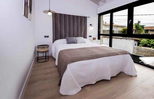 a bedroom with a large bed and a large window at AdosadoDuplex Marea Baja 3 Zona Playa Ideal familias parejas y amigos in Llanes