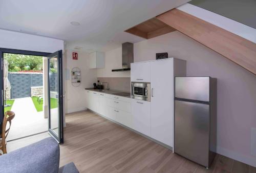 uma cozinha com armários brancos e um frigorífico de aço inoxidável em adosadoduplex adaptado en zona de playa ideal familias em Llanes