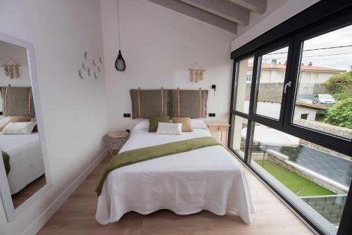 a bedroom with two beds and a large window at ADOSADO-DUPLEX ADAPTADO zona de playa y montaña in Llanes