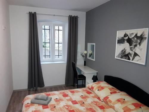 a bedroom with a bed and a desk and a window at Apartments Vidulić in Mali Lošinj