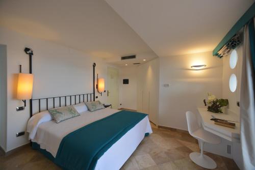 a hotel room with a bed and a desk at El Faro Hotel & Spa in Porto Conte