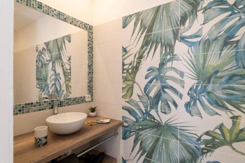 ein Bad mit einem Waschbecken und einem Wandbild aus Blättern in der Unterkunft Bien d'exception en face du Palais des Papes in Avignon