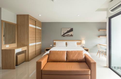 a bedroom with a bed and a couch at JK LIVING Hotel And Service Apartment in Chachoengsao