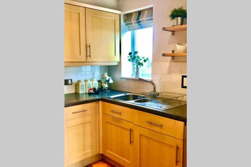 a kitchen with wooden cabinets and a sink and a window at Stylish Quayside 2 bed apartment with beautiful river views in Newcastle upon Tyne