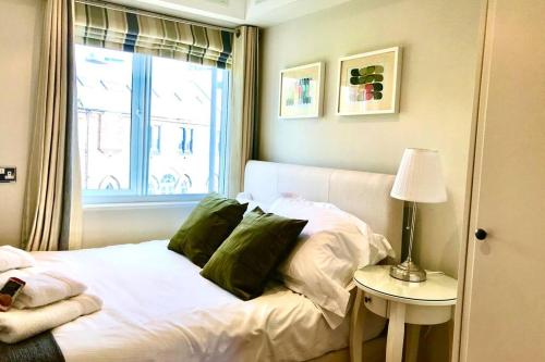 a bed with green pillows in a room with a window at Stylish Quayside 2 bed apartment with beautiful river views in Newcastle upon Tyne