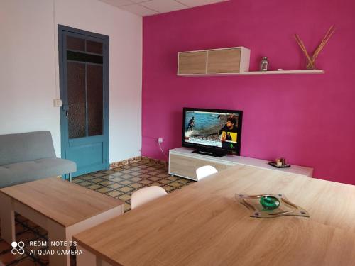 uma sala de estar com uma mesa e uma parede rosa em Apartamento vinamar em Vinarós