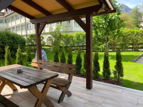 a wooden picnic table and a wooden bench on a patio at Im Kurpark in Bad Ischl