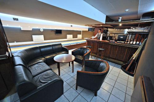 a bar with leather furniture and a woman standing at a counter at Hotel Sport in Bełchatów