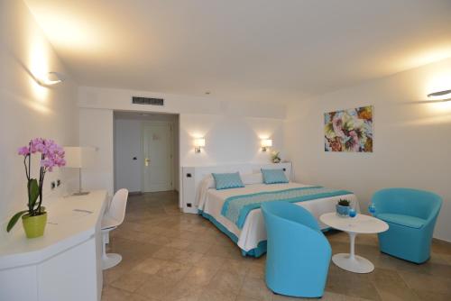 a bedroom with a bed and a table and chairs at El Faro Hotel & Spa in Porto Conte