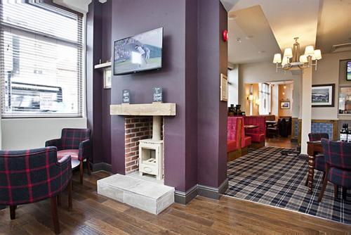 a waiting room with a fireplace and a tv on a wall at The Dickens Bar & Inn in Scarborough