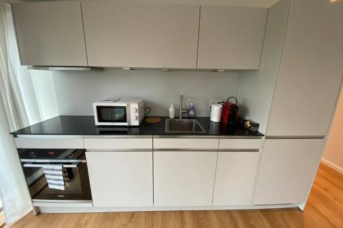 a kitchen with white cabinets and a microwave at Luxury Duplex in Luxembourg Center Free Parking 5 min walk to the tram in Luxembourg