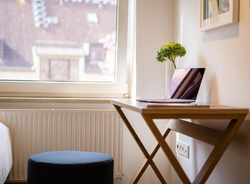 a desk with a laptop on it next to a window at Hotel Wetterstein in Munich