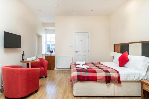 a bedroom with a bed and a red chair at Victoria Court Suites - Aberdeen in Aberdeen