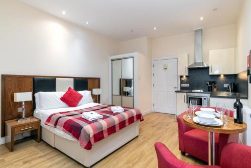 a bedroom with a bed and a table and a kitchen at Victoria Court Suites - Aberdeen in Aberdeen