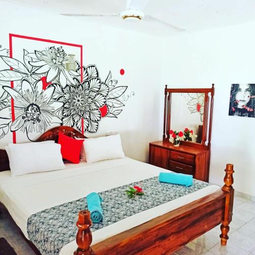 a bedroom with two beds with a flower mural on the wall at Singhe House in Dickwella