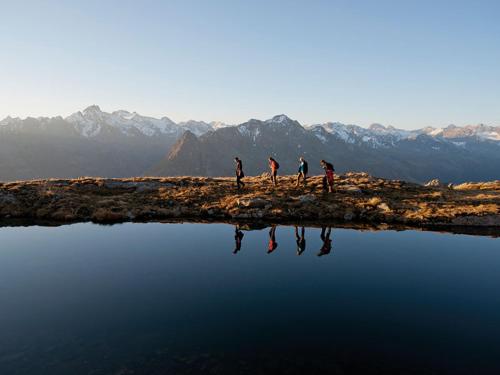 a group of people walking on a hill next to a body of water at Augl‘s Hof in Ischgl